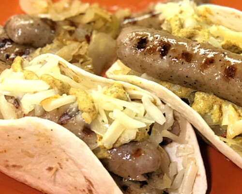 Grilled brats nestled in a warm flour tortilla, topped with sauerkraut, shredded Swiss cheese, and mustard.