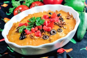 A white casserole dish loaded with enchilada casserole.