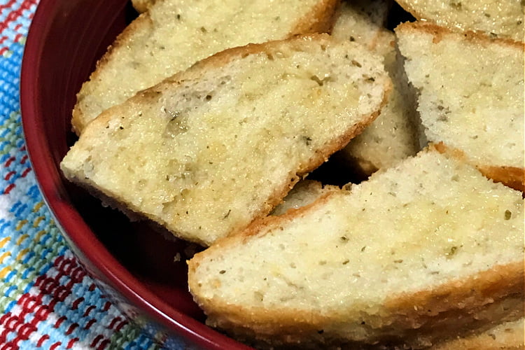 Fat slices of buttered peasant bread in a serving bowl.