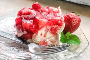 A side view of a piece of Strawberry Angel Dessert with a fork on a plate.