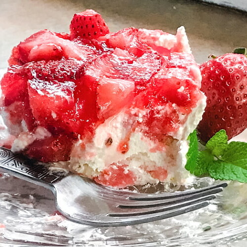 A side view of a piece of Strawberry Angel Dessert with a fork on a plate.