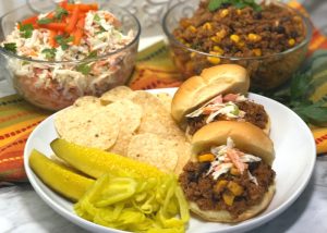 sloppy joes on a plate with chips and pickles