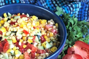 Corn salad with vegetables in a blue bowl.