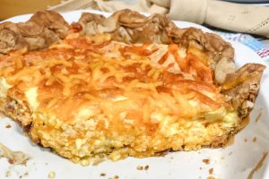 A partial ham and cheese quiche in a white pie plate.