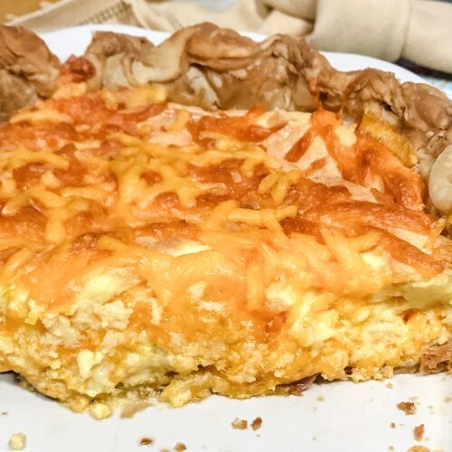 A partial ham and cheese quiche in a white pie plate.