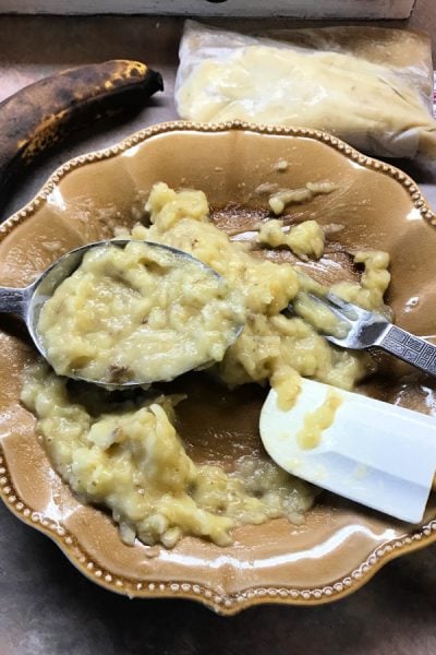 Mashed bananas with measuring spoon on plate.