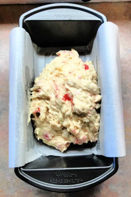 Loaf pan with a piece of parchment and banana bread batter on top.