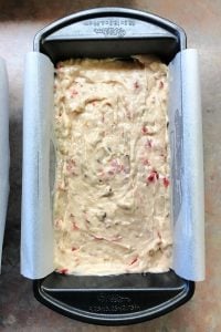 Loaf pan full of banana bread batter that is smoothed out on top.