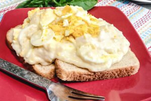 Creamed Eggs on Toast served on a red plate.