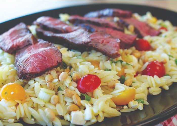 Orzo pasta with veggies, topped with medium rare slices of steak - perfectly delicious!