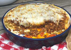 Half a spaghetti pie in a round casserole dish.
