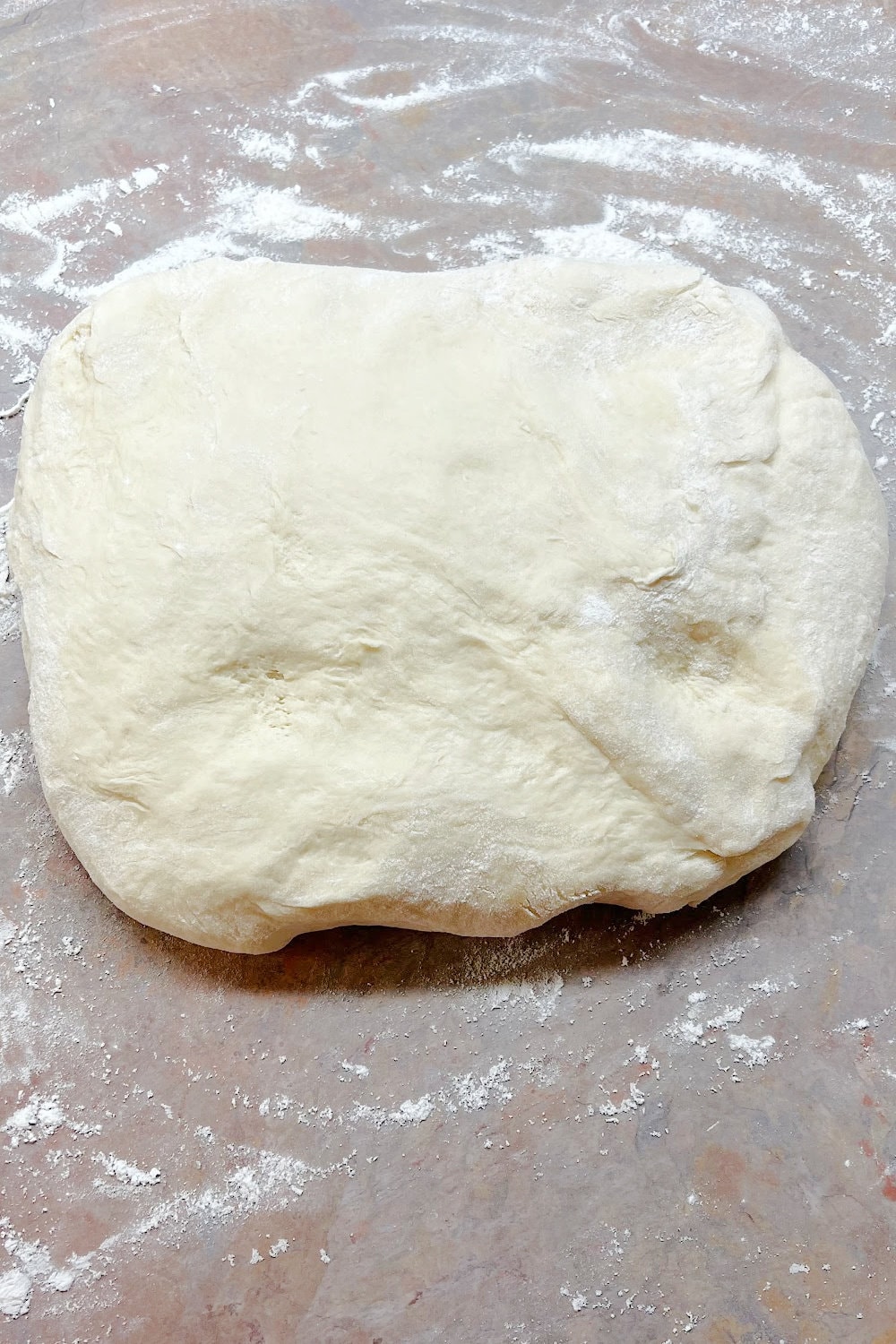 Cinnamon roll dough formed into a rough rectangle. 