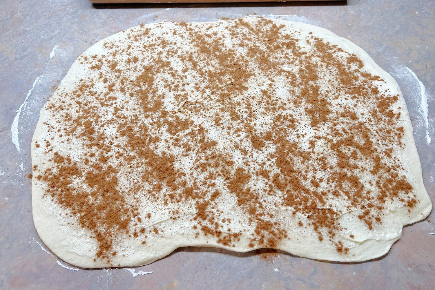 Cinnamon roll dough sprinkled with cinnamon .