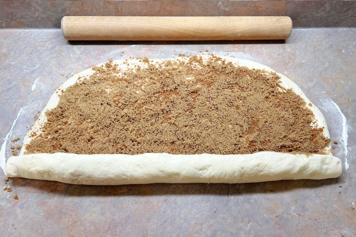 Cinnamon roll dough beginning to be rolled up. 