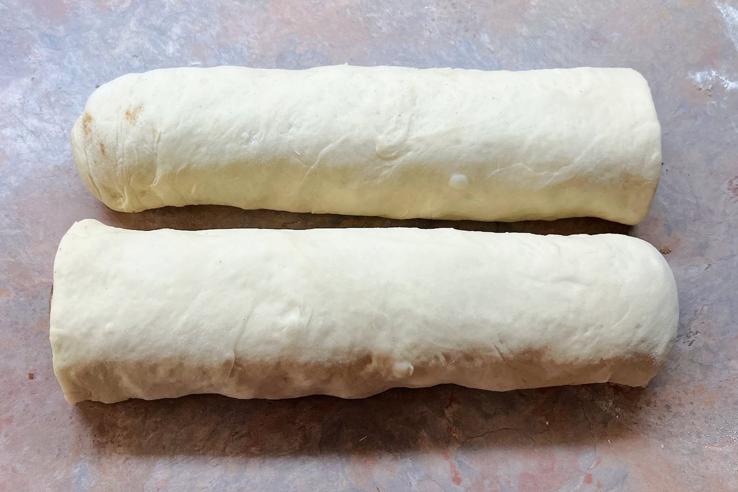 The cinnamon roll dough log cut into two equal halves. 