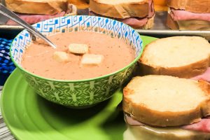 A bowl of Creamy Tomato Dill Soup with grilled cheese sandwiches.