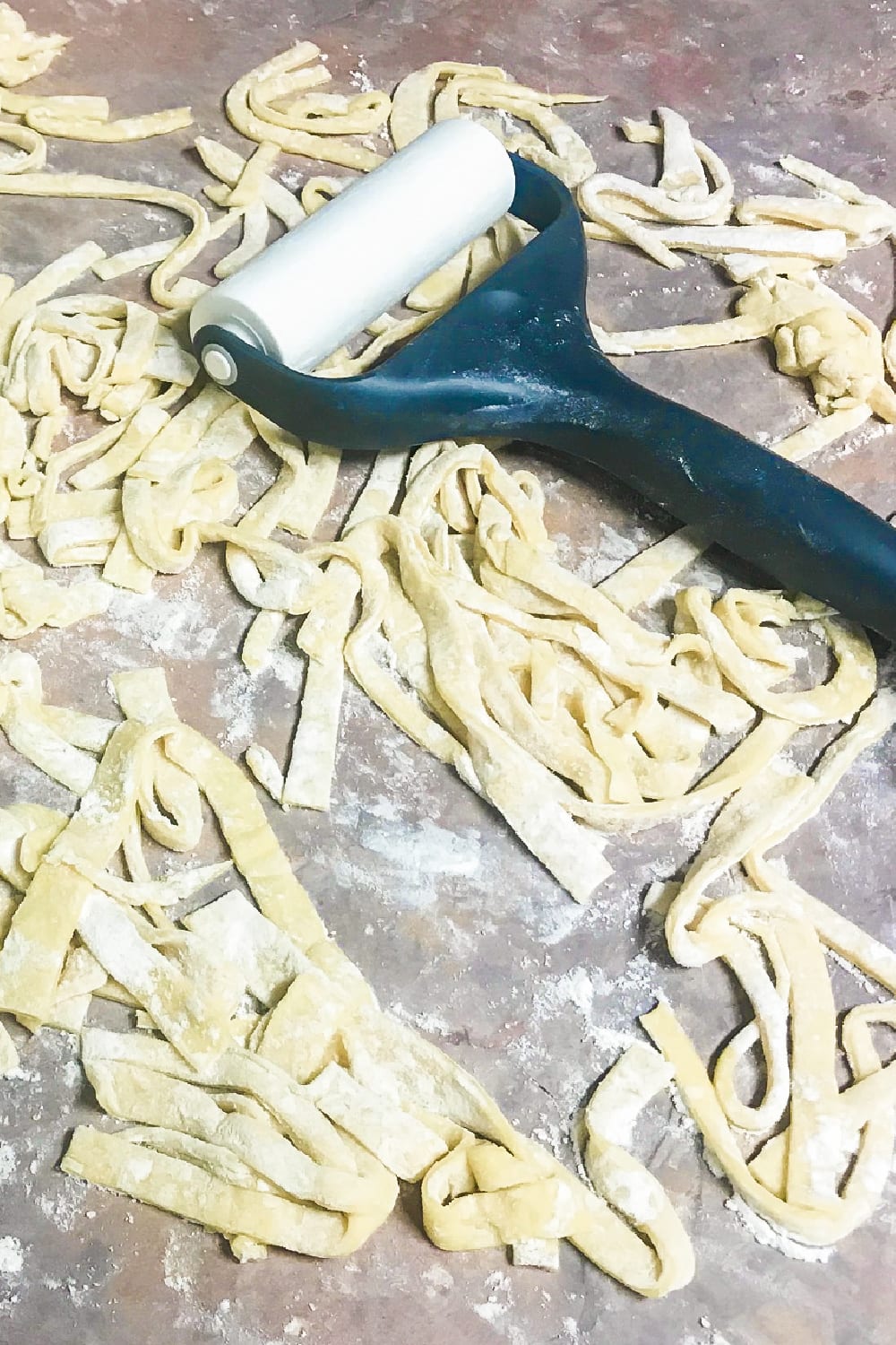 a fresh batch of egg noodles with a rolling pin on the counter