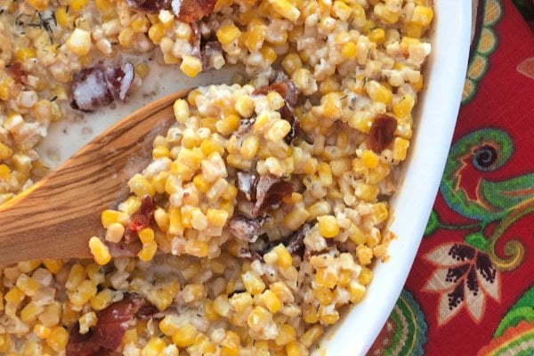 A creamy corn casserole topped with bacon and baked in a cast iron skillet or casserole dish.