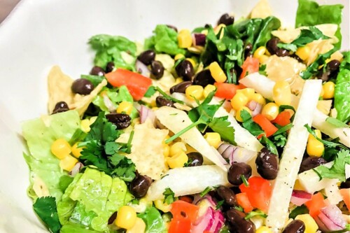 A mixed greens salad with vegetables and black beans.