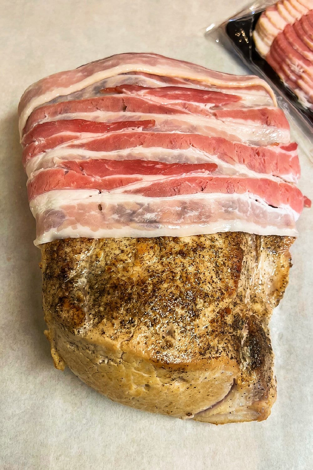 A seasoned pork loin roast that's half wrapped with strips of bacon. 