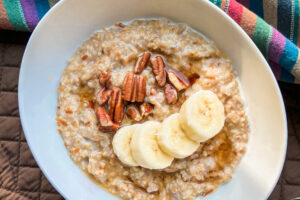 A white bowl full of steel cut oats with sliced bananas.