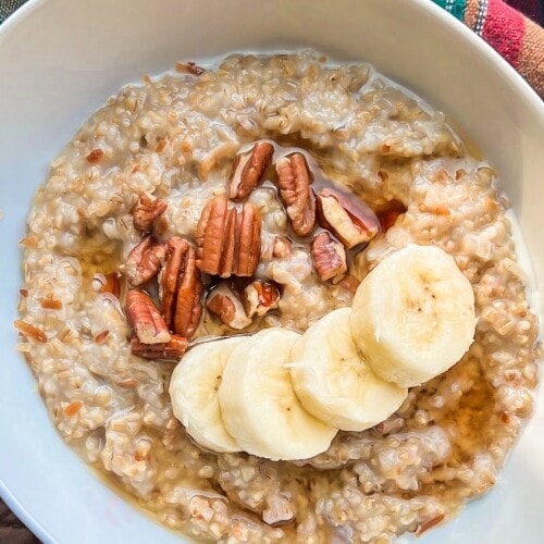 A white bowl full of steel cut oats with sliced bananas.