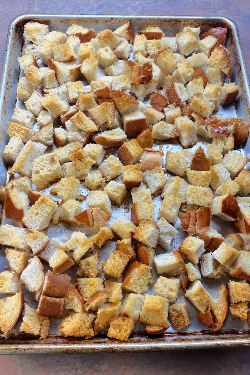 Bread cubes toasted until golden brown on a baking sheet.
