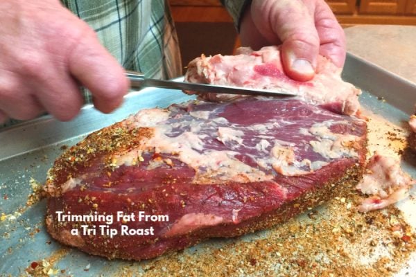 Use a sharp knife to trim the fat from a tri tip roast. 