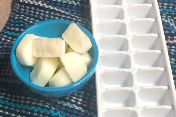 Frozen yogurt cubes in a bowl beside an ice cube tray.