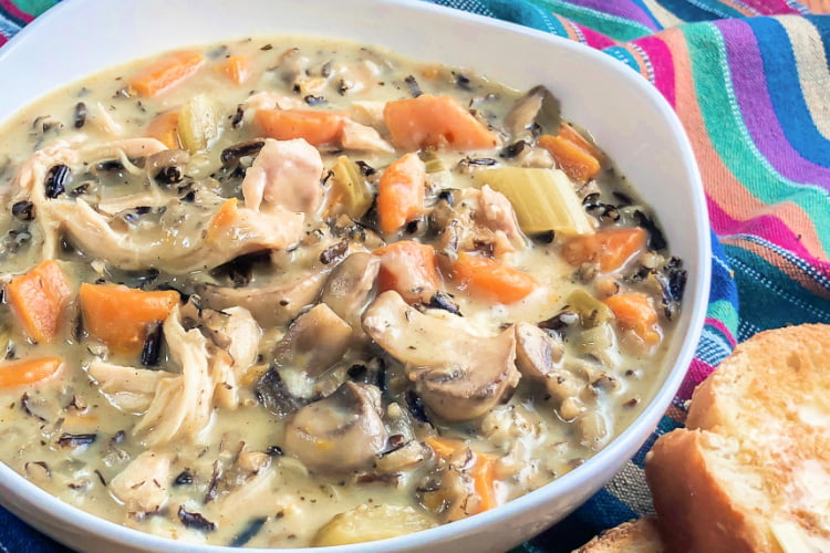 A big bowl of chicken and wild rice mushroom soup with toasted bread on the side.