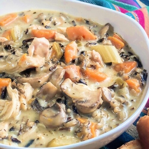 White bowl that is loaded with Creamy Chicken and Wild Rice Soup.