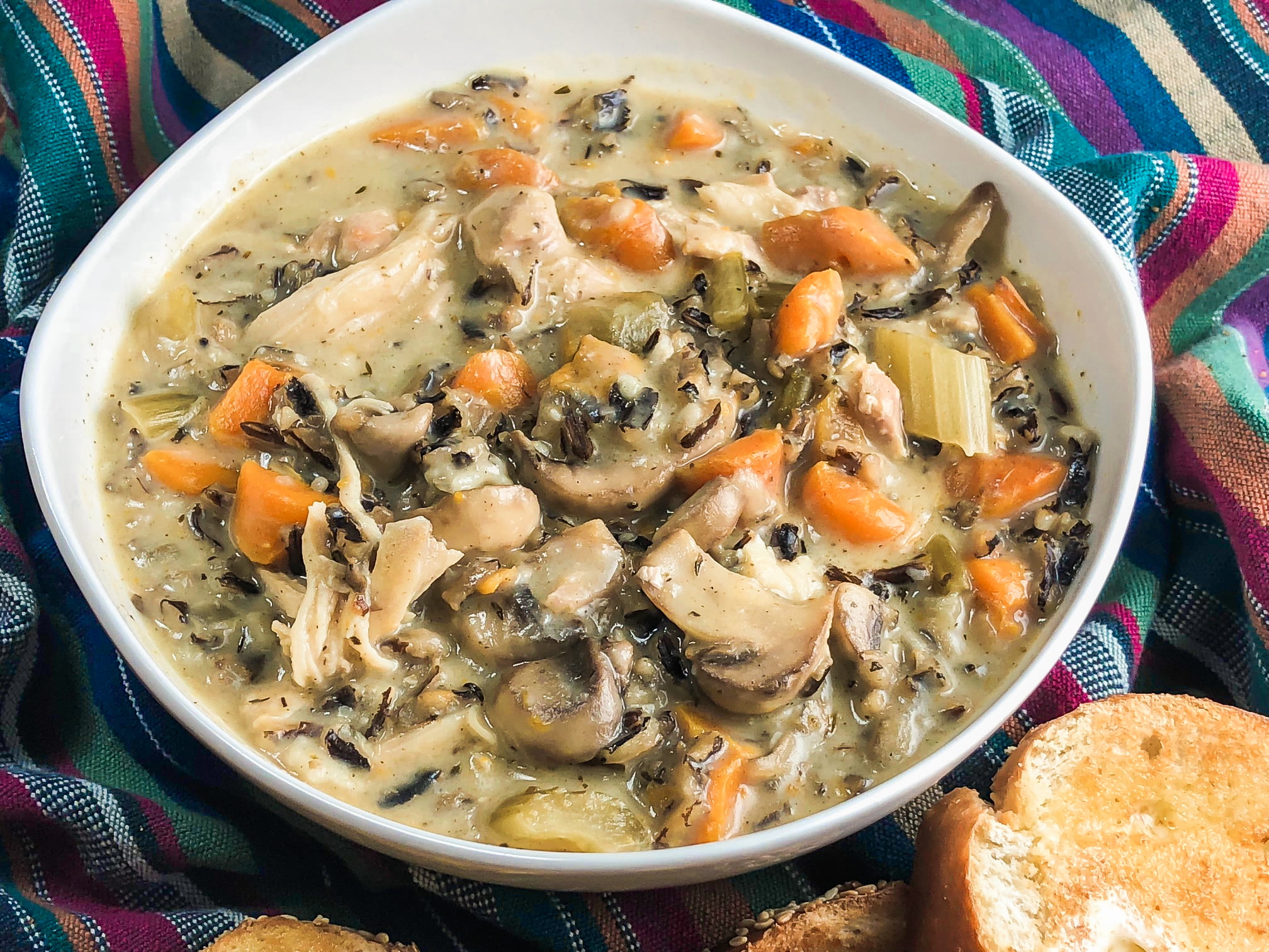 A large bowl filled to the brim with chicken and wild rice soup.