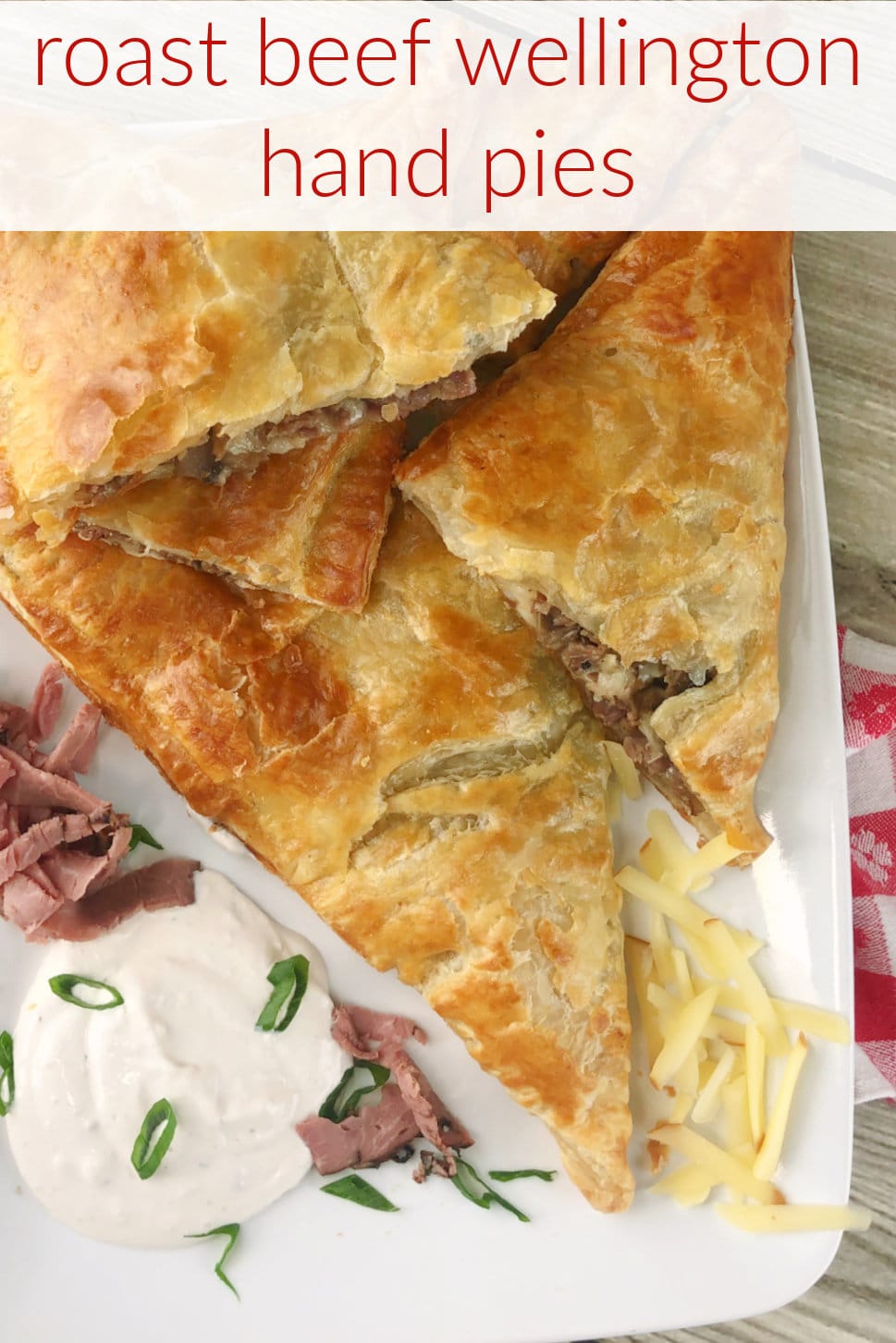 Roast Beef Wellington packets on a white platter with creamy sauce on the side. 