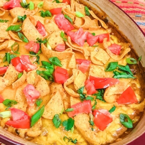 A pan of chili cheese tamale dip topped with corn chips.