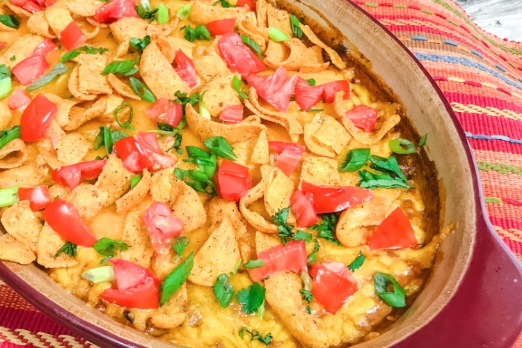 A pan of chili cheese tamale dip topped with corn chips.