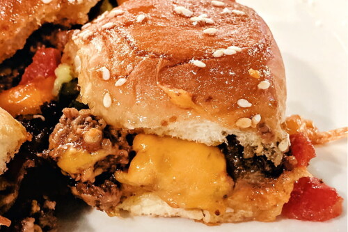 Side view of a cheeseburger slider with ground beef and melted cheese.