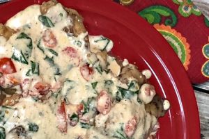 Chicken breasts smothered with a creamy white sauce that has tomatoes and spinach.