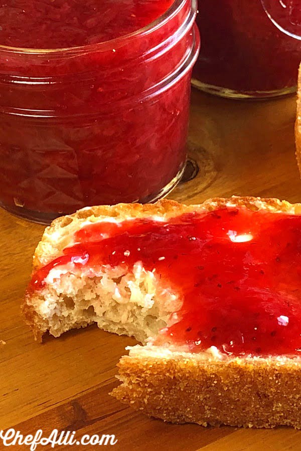 A slice of English Muffin Bread that is slathered with strawberry jam. 