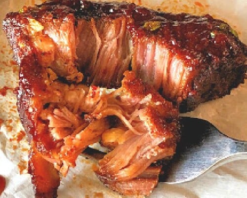 a country style rib with bbq sauce and a fork.