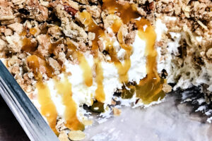 A pan of butter brickle ice cream dessert with caramel dripping down the edge.