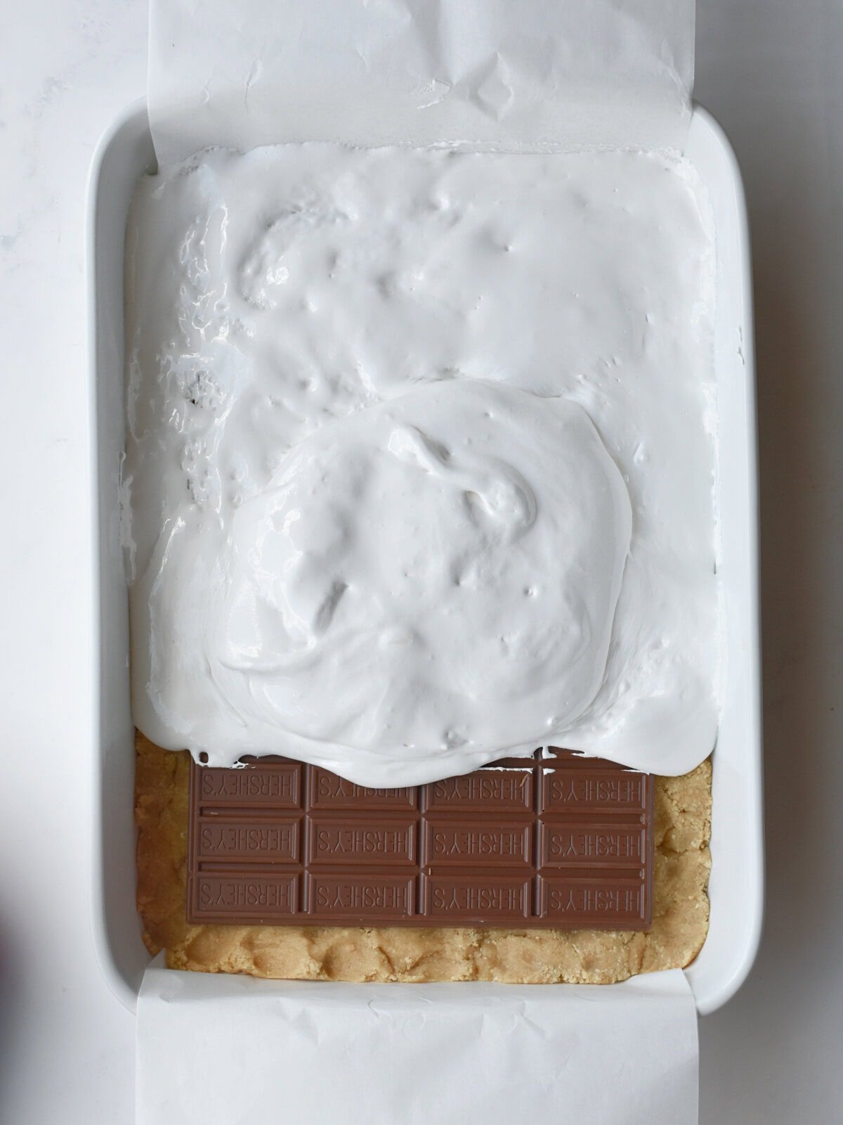 Layering dessert ingredients with dough, chocolate and marshmallow fluff. 