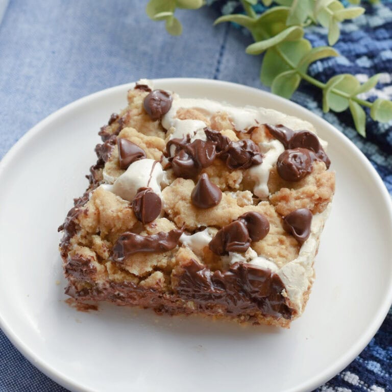 A rich and chewy smores cookie bar on a white plate.