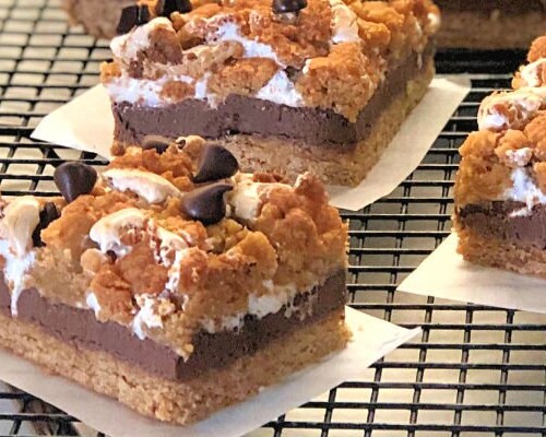 Calling all s'mores lovers!! These thick and yummy cookie bars are loaded with graham cracker flavor and oozing with warm chocolate and gooey marshmallows. We can never get enough of these Golden S'mores Cookie Bars and they are incredibly easy to make in your favorite 9 x 13 baking dish.  No campfire required. :) #grahamcrackers #marshmallows #chocolate #campfire #cookies