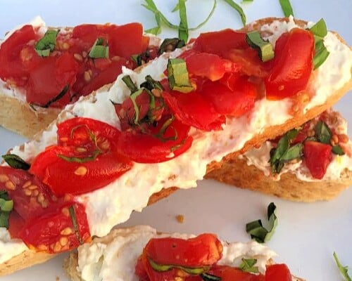 Who knows how many times we've made this easy appetizer when there's tons of homegrown tomatoes coming in from the garden! These Tomato Crostini combine the crispy/chewy texture of the bread with the creamy feta spread and the luscious vine-ripened tomatoes with fresh basil.  #HomegrownTomatoes #Tomatoes #Basil #Appetizer #Feta