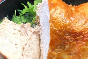 A golden brown turkey breast that has been sliced on one side to reveal the internal part of the turkey breast.