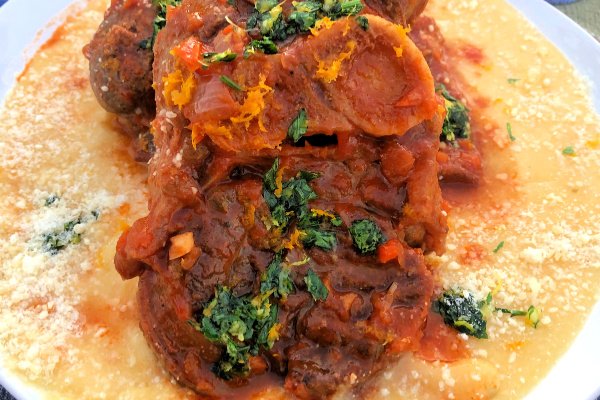 Two pork osso bucco piled on top of each other over a bed of warm parmesan polenta.