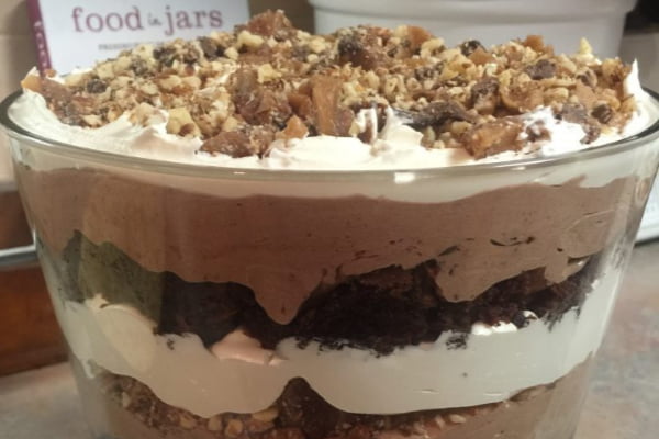 Layered chocolate and toffee trifle in a clear glass trifle bowl.