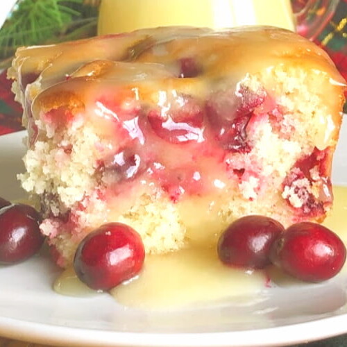 A piece of yellow cake with cranberries on a plate.