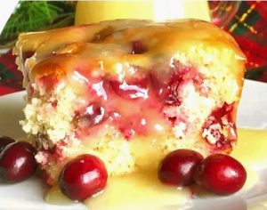 A square slice of Cranberry Butter Cake with Vanilla Sauce and fresh cranberries.