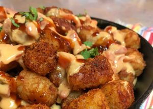 Twisted Mexican Hot Tots layered into a skillet with queso.